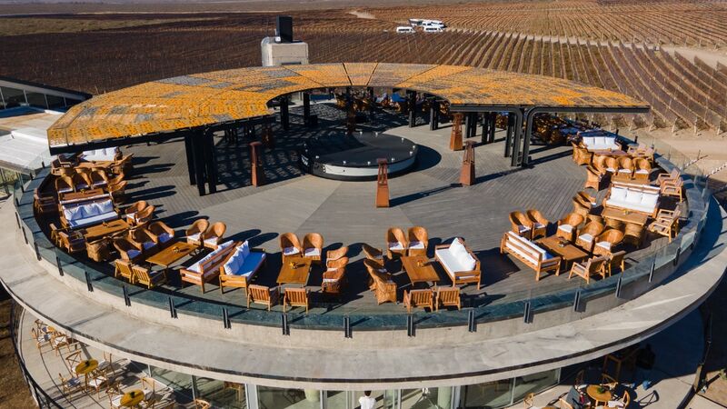 Vista aérea do rooftop circular da bodega com lounges e vinhedos ao redor